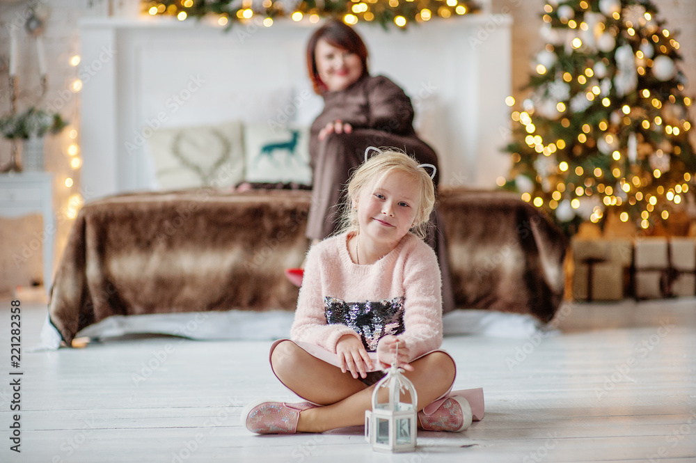 The beautiful woman with the daughter indoors with a Christmas interior The beautiful woman with the daughter indoors with a Christmas interior