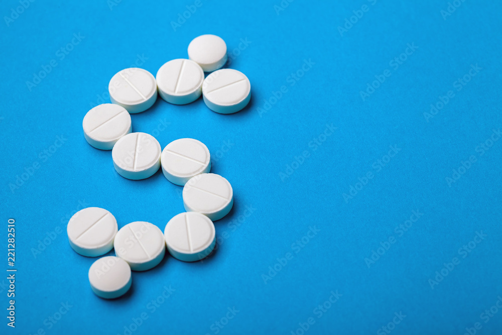 pharmacological industry business concept dollar sign laid out of round white tablets on a blue background.