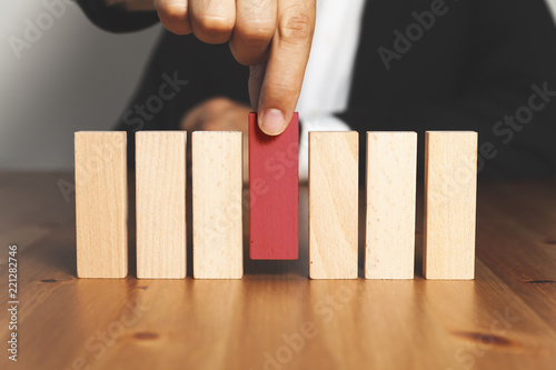 Businessman hand arranging or picking red wood block