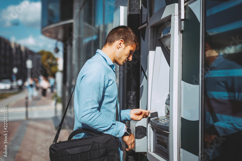 Young businessman withdraws money from the ATM photo