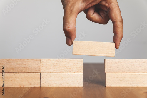 Foto Man solving problems by building bridge with wooden block