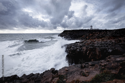 Stormy seascape and lighthouse on rocky coastline. Carvoeiro Cape, Peniche, Portugal