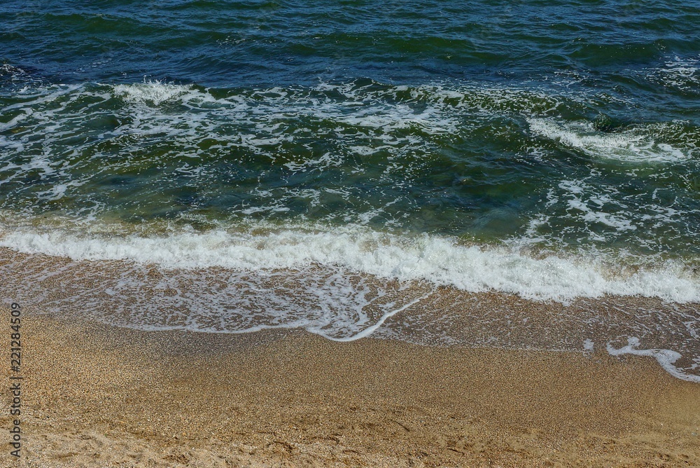 blue green sea waves with white foam on brown sand