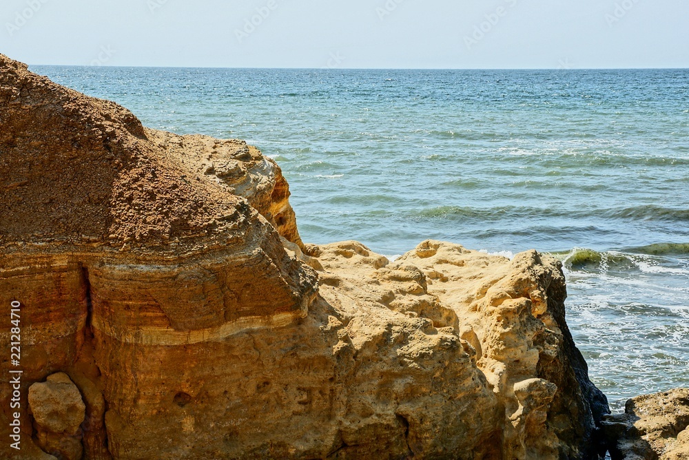 big brown rock on a background of sea waves and blue sky