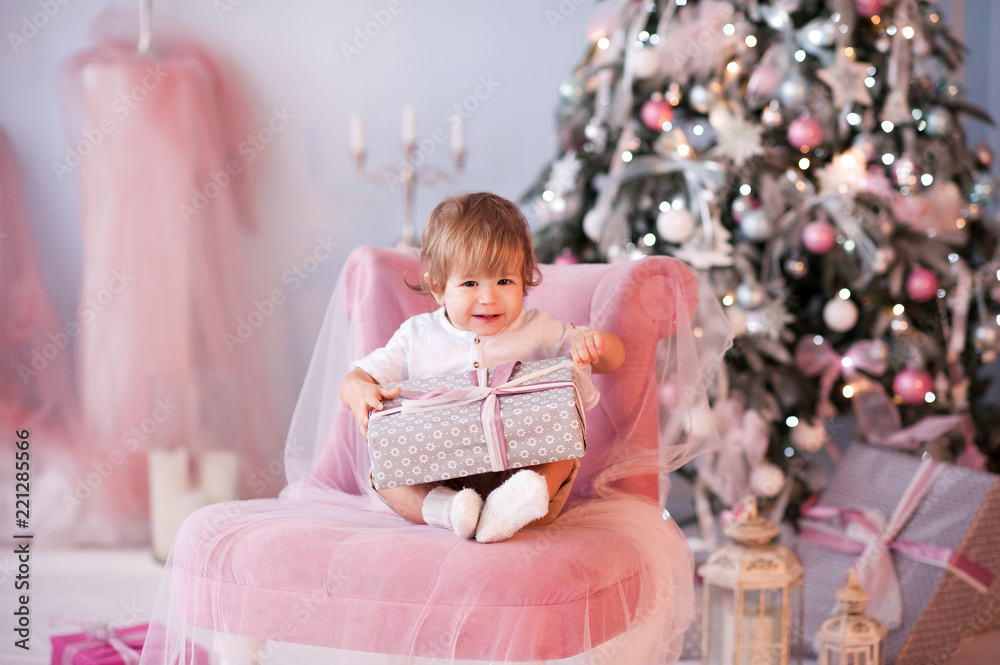 Baby boy 1 year old open Christmas presents over decorated tree in room. Looking at camera. Winter season. Baby boy 1 year old open Christmas presents over decorated tree in room. Looking at camera. Winter season.