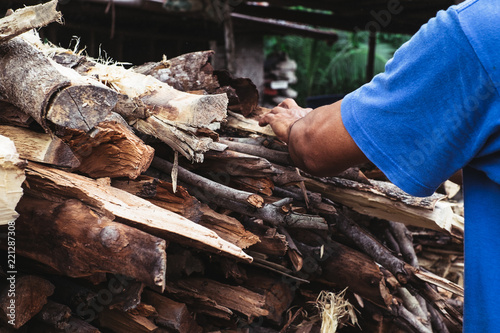 Man's hand to gather uneven chopped fire woods. Selective focus.