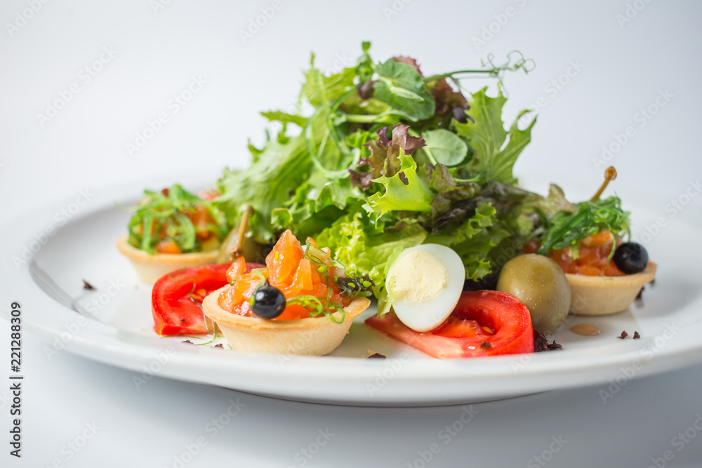Fresh salad with salmon, olives, green, tomatoes and quail eggs