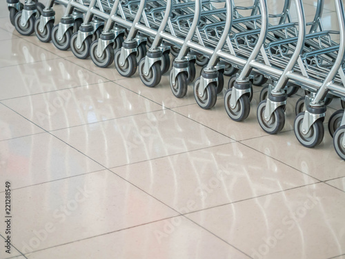 Row of airport trolleys on grids tiles floor with reflection.