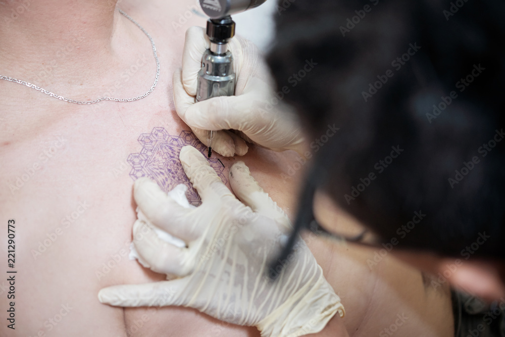 Professional tattoo artist using special machine when applying ink over  stencil Stock Photo | Adobe Stock