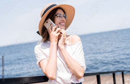 Young pretty traveler woman calling and talking phone, wifi conection on sunny beach, travel alone with backpack at hot tropical country, casual outfit, trip tour agensy, adventure mood. photo