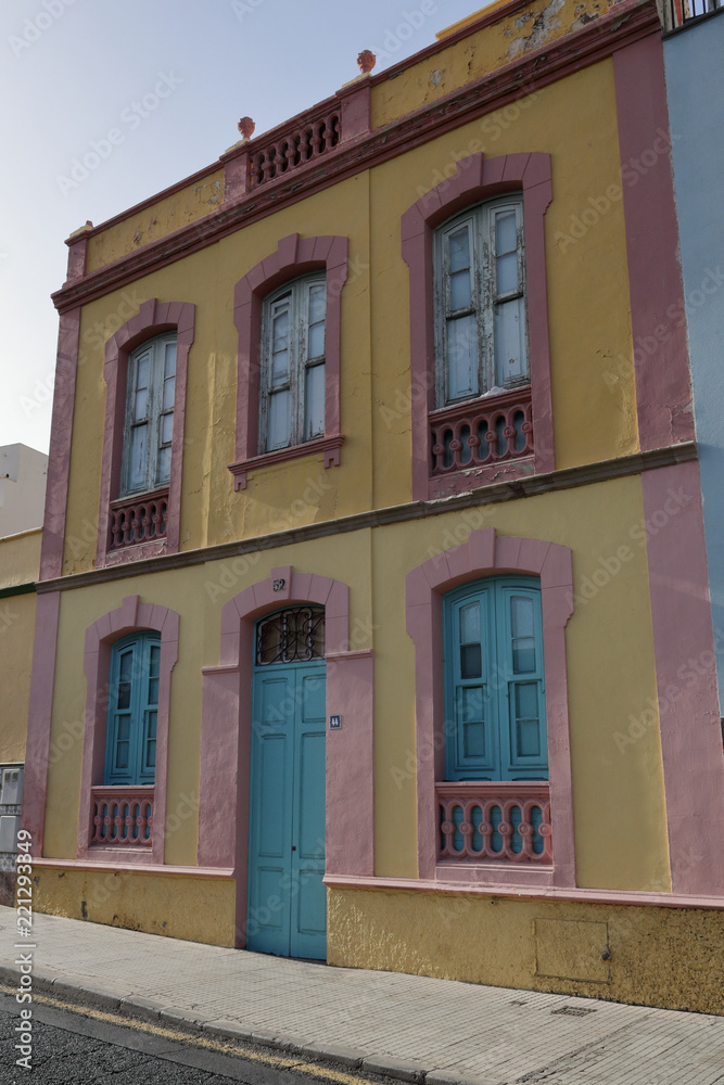 Fototapeta premium A 19th century pink and yellow building with a blue door and five windows in Santa Cruz de Tenerife, Spain