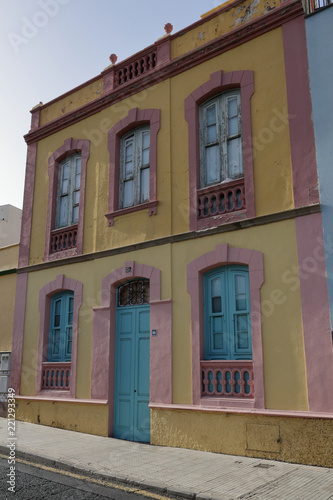 A 19th century pink and yellow building with a blue door and five windows in Santa Cruz de Tenerife, Spain © Isacco