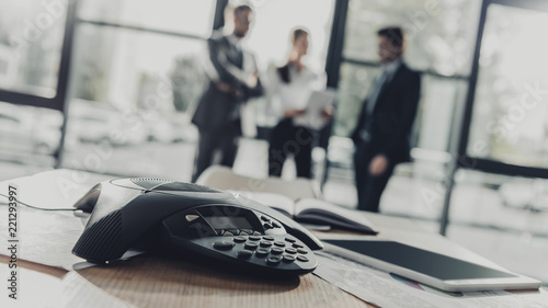 Принти на полотні close-up shot of conference phone with blurred business people on background at