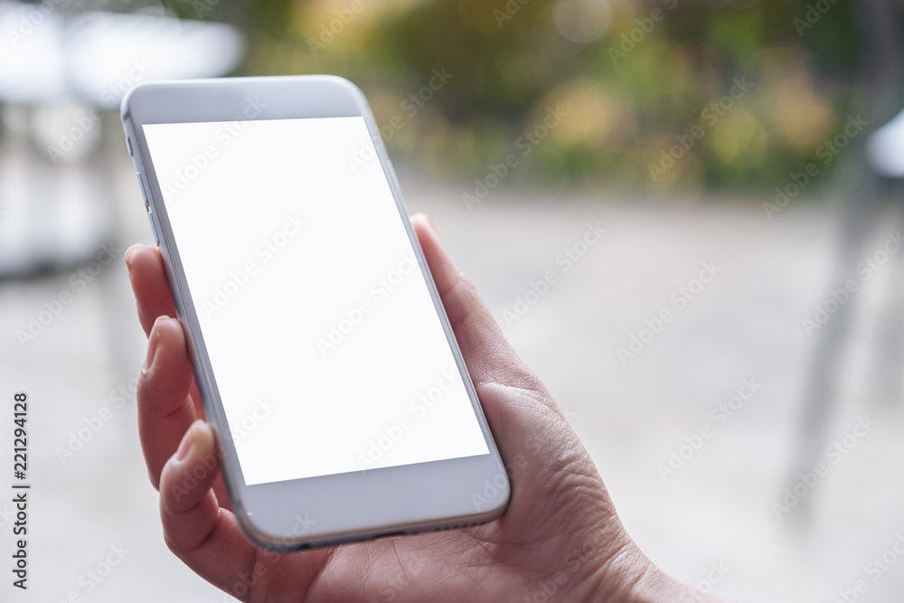 Mockup image of hand holding and using mobile phone with blank white screen with blur background