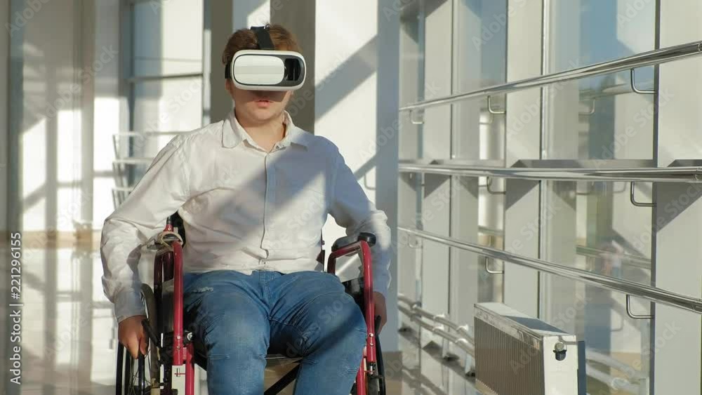 disabled man on a wheelchair at a window uses a helmet of virtual reality disabled man on a wheelchair at a window uses a helmet of virtual reality