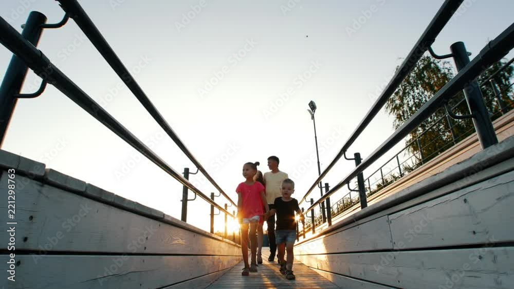 A walk in the Park. Young family walking on a wooden platform. The kids run ahead, parents following behind. A walk in the Park. Young family walking on a wooden platform. The kids run ahead, parents following behind.