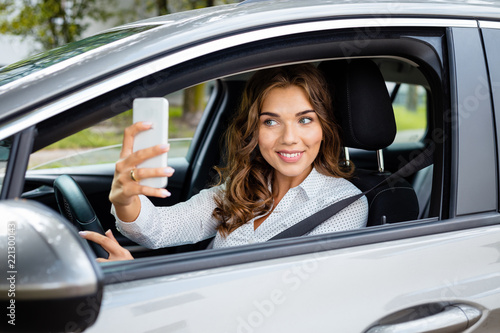 Young businesswoman taking selfie while driving a car