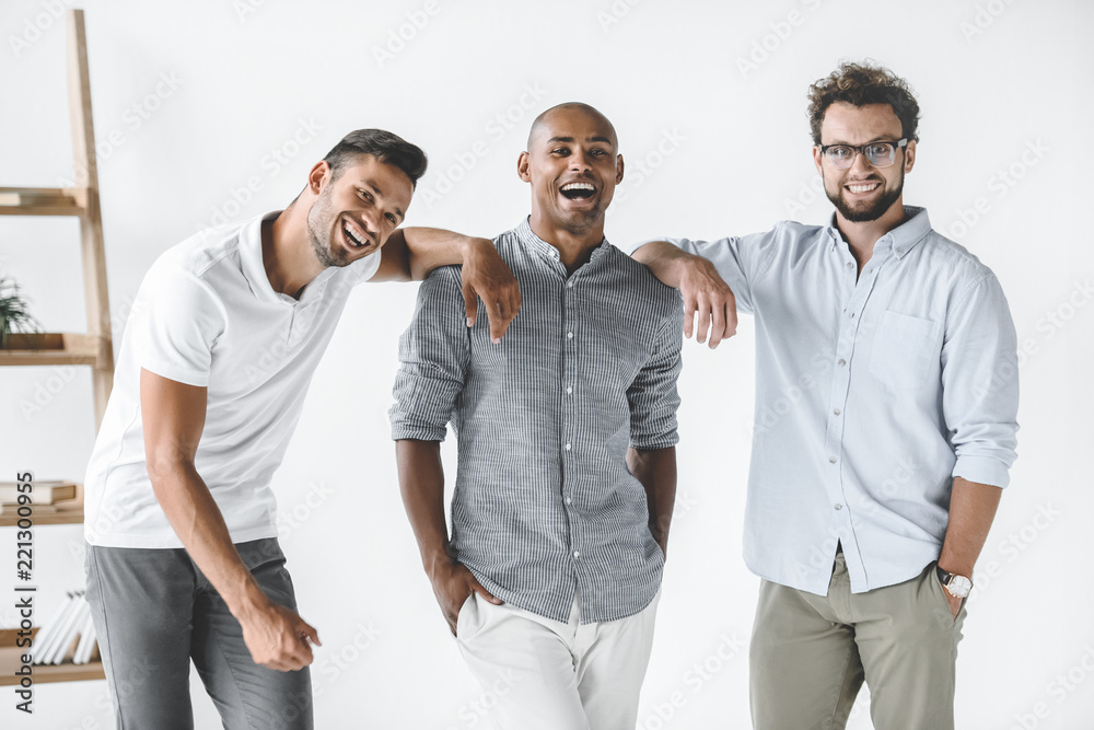 multiethnic group of young smiling businessmen standing in light office