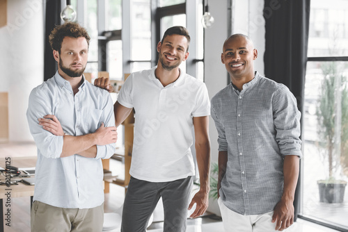 multiethnic young businessmen looking at camera while standing in office © LIGHTFIELD STUDIOS