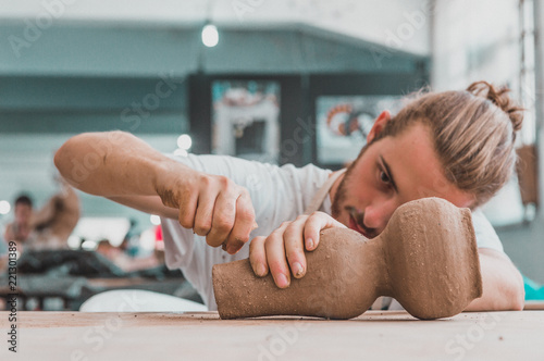 Young pottery artist working on his clay pot in a studio