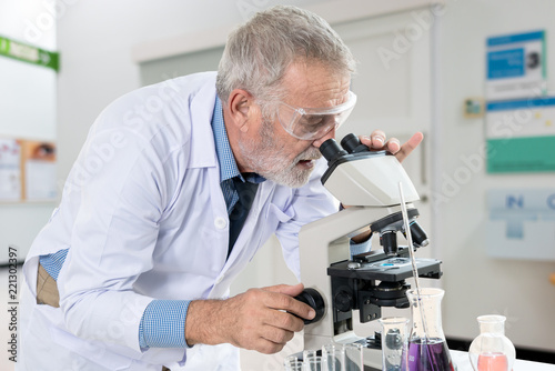 The senior doctor looking in Microscope at laboratory