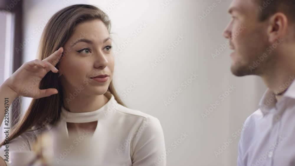 Two young people are sitting in a cafe. They are smiling and chatting. Man and woman are sitting in the restaurant at the table during break. Couple are talking and drinking coffee. Two young people are sitting in a cafe. They are smiling and chatting. Man and woman are sitting in the restaurant at the table during break. Couple are talking and drinking coffee.
