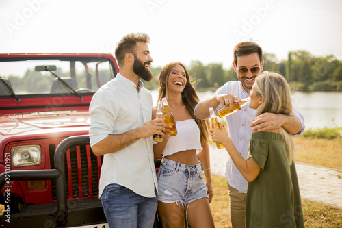 Young people drinking and having fun by car