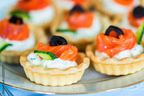 Tartlets with cheese, salmon and olives close