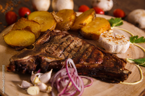steak t-bone on wooden backing and baked potatoes