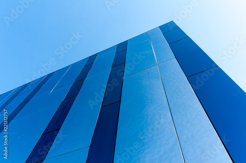 Modern blue office building corner on blue sky background. Bottom view
