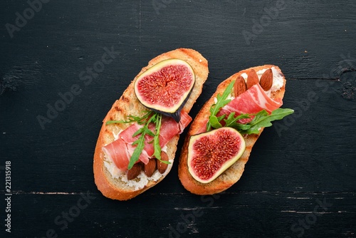 Sandwich with figs, prosciutto and cheese. On the old background. Healthy food. Free space for text. Top view.