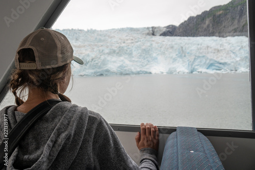 Back facing female stares out the window on a tourist boat in Alaska, visiting Holgate Glacier in Kenai Fjords National Park photo