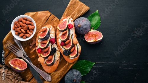 Sandwich with figs, wild berries and cheese. On the old background. Dessert. Free space for text. Top view.