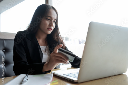 Asian businesswoman sitting at sofa working Laptop on table in coffee shop