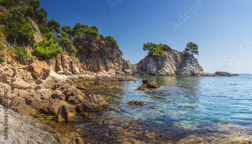 Amazing view on rocks, stones and sea shore in Spanish Mediterranean Sea, Bay in Lloret de Mar, Costa Brava, Spain. Seascape of rocky sea beach on summer day. Landscape of mountains sea nature.