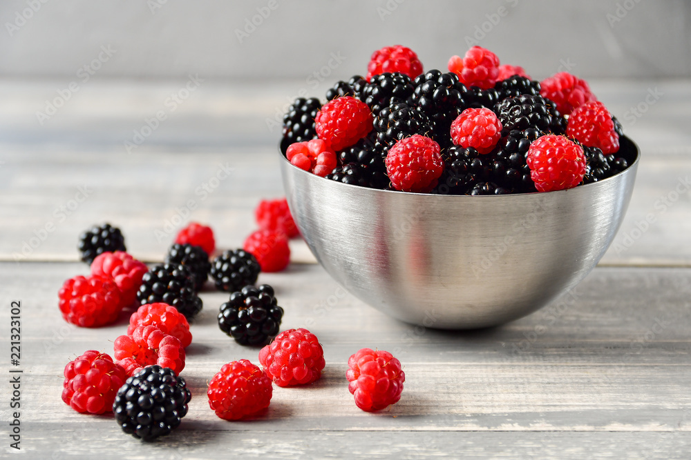 fresh organic blackberries and raspberries in a metal bowl on a wooden table, concept of diet, vitamins and antioxidants. selective focus and copy space fresh organic blackberries and raspberries in a metal bowl on a wooden table, concept of diet, vitamins and antioxidants. selective focus and copy space