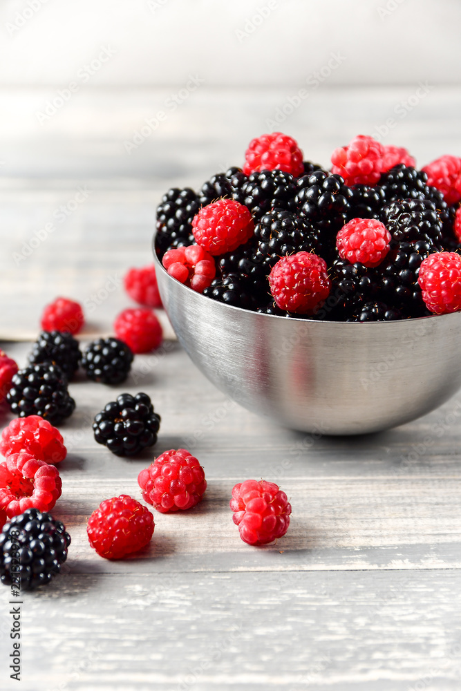 fresh organic blackberries and raspberries in a metal bowl on a wooden table, concept of diet, vitamins and antioxidants. selective focus and copy space fresh organic blackberries and raspberries in a metal bowl on a wooden table, concept of diet, vitamins and antioxidants. selective focus and copy space