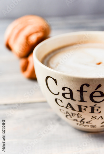  Breakfast is a large beige Cup of coffee with milk and croissants on a wooden table. on the Cup inscription in French (top down: mocha coffee, coffee with milk, coffee without sugar)
