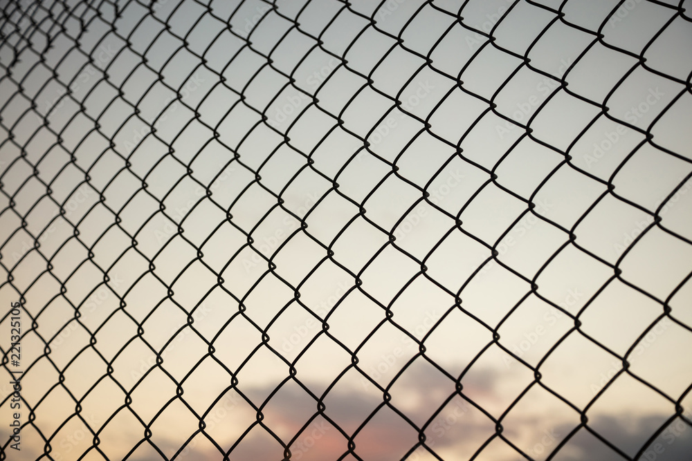 Fototapeta premium Sky through wire mesh fence. Blur background, close up view of link cage.
