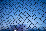 Blue sky through wire mesh fence. Blur background, close up view of link cage, wallpaper.