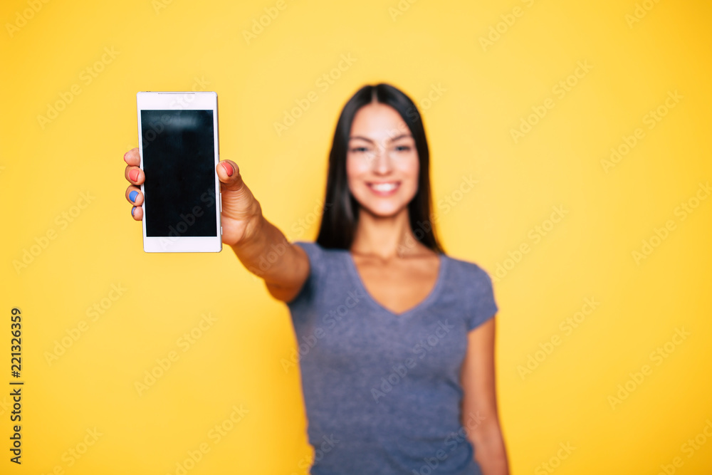 Choice it! Technology, mobile, equipment for communication. Young beautiful woman shows right in camera the blank screen of smart phone on yellow background Choice it! Technology, mobile, equipment for communication. Young beautiful woman shows right in camera the blank screen of smart phone on yellow background