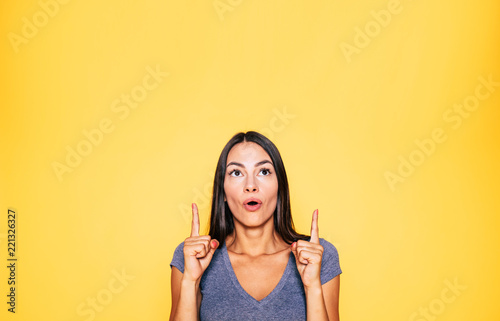 Photo of young excited beautiful happy brunette woman  girl pointing away and smile isolated on yellow background banner