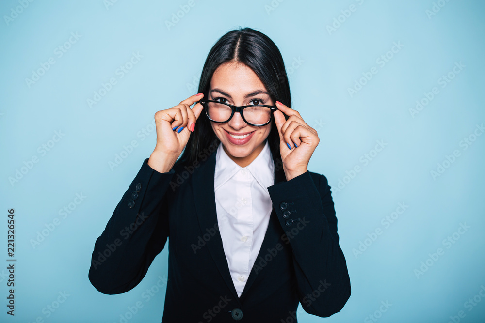 Excited cute attractive smiling business woman in eyeglasses and full suit looks into the camera with smile
