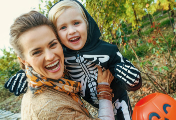 smiling modern mother and daughter on Halloween outdoors