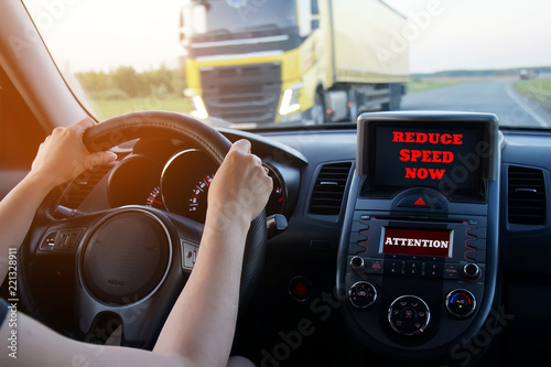 the girl driving rushes on the route, an inscription on the monitors "reduce speed now" and "attention".