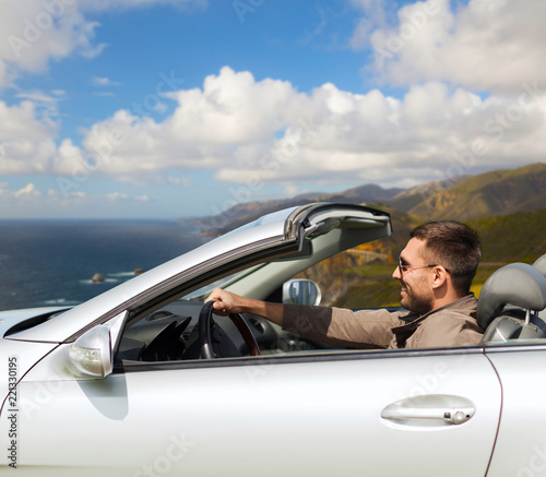 road trip, travel and people concept - happy man driving convertible car over big sur hills background in california