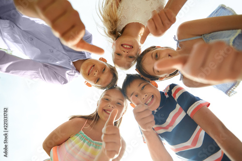 childhood, friendship and gesture concept - group of smiling happy children showing thumbs up in circle