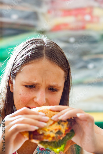 Portrait of young teenage girl eat burger. Girl trying to eat fast food