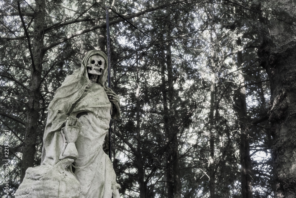 Statue of a skullfaced grim reaper made of stone with a tall scythe in his left hand. Statue of a skullfaced grim reaper made of stone with a tall scythe in his left hand.