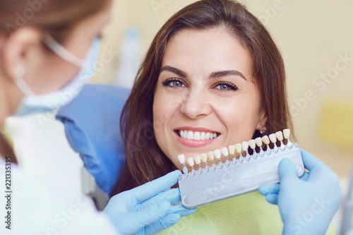 Teeth whitening dental clinic. Closeup of a young woman with beautiful smile at the dentist. photo